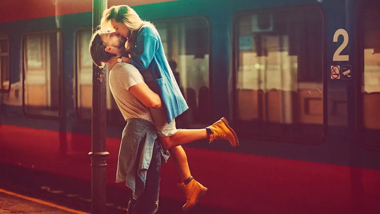 Un uomo solleva una donna in un bacio appassionato alla stazione. L'infatuazione significato è evidente nel loro abbraccio.