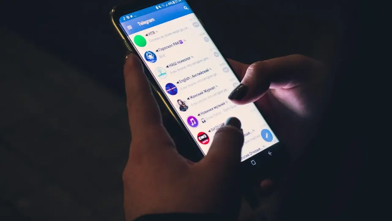 Mani che scorrono su Telegram, mostrando cinque chat attive: notizie, oroscopo, psicologia, inglese e musica.