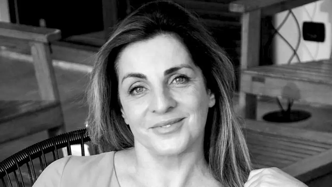 Ritratto in bianco e nero di una donna sorridente, con i capelli lunghi e mossi. "Ciao, come stai?" è una domanda inutile se il tuo sguardo è così sereno.