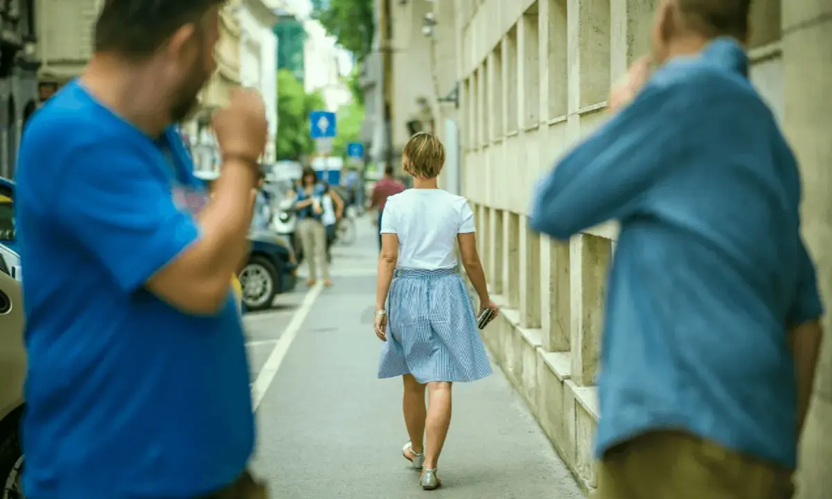 Uomo in strada fa gesti volgari a donna, un esempio di catcalling reato.
