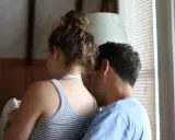Un uomo sussurra all'orecchio di una donna, un momento intimo che rivela un'attrazione fortissima per una persona.