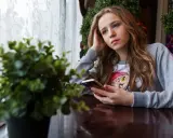 Ragazza pensierosa al telefono, con un'espressione che sembra dire "lei mi scrive e poi sparisce".