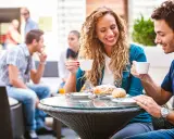 Coppia al bar, lei ride sorseggiando caffè. Un indizio di psicologia: come capire se un uomo è interessato?