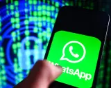 Un dito tocca lo schermo di uno smartphone con il logo WhatsApp, simbolo di cosa è una chat moderna. Sullo sfondo, un lucchetto digitale e codice binario suggeriscono sicurezza e comunicazione.