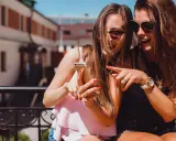 Due amiche ridono guardando il telefono, un momento perfetto per decidere cosa raccontare ad una ragazza.