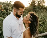 Un uomo e una donna si guardano con uno sguardo innamorato, circondati da una vegetazione lussureggiante al tramonto.