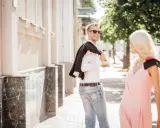 Un uomo sorride, voltandosi per guardarti negli occhi da lontano, con la giacca sulla spalla.