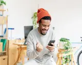 Uomo con cappello arancione e occhiali, felice mentre guarda il telefono. Lei mi guarda le storie ma non mi scrive, ma lui è contento lo stesso!