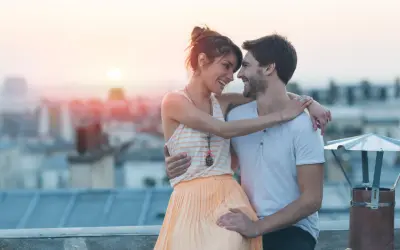 Coppia sul tetto al tramonto, sguardi complici e abbracci che rivelano segnali nascosti di attrazione.