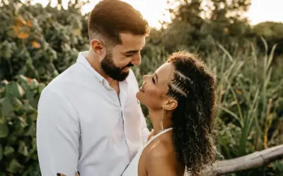 Un uomo e una donna si guardano con uno sguardo innamorato, circondati da una vegetazione lussureggiante al tramonto.