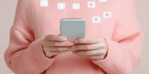 Mani con smartphone, icone di like e play fluttuano, evocando la psicologia di chi fa orbiting e cerca conferme digitali.
