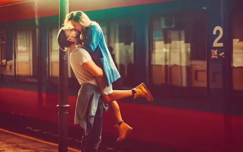 Un uomo solleva una donna in un bacio appassionato alla stazione. L'infatuazione significato è evidente nel loro abbraccio.