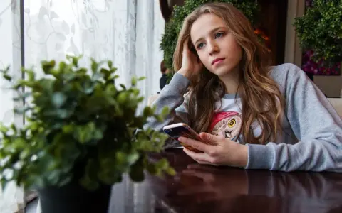 Ragazza pensierosa al telefono, con un'espressione che sembra dire "lei mi scrive e poi sparisce".