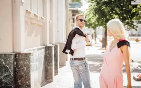 Un uomo sorride, voltandosi per guardarti negli occhi da lontano, con la giacca sulla spalla.