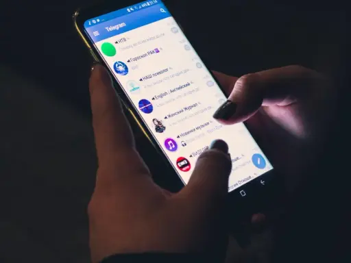 Mani che scorrono su Telegram, mostrando cinque chat attive: notizie, oroscopo, psicologia, inglese e musica.