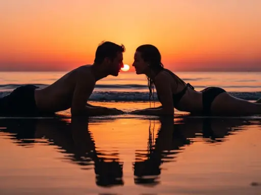 Coppia sdraiata sulla spiaggia al tramonto, sguardi intensi, si sente l'attrazione tra due persone.