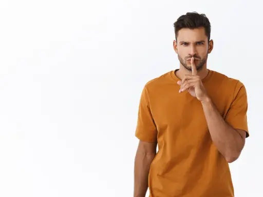 Uomo con dito sulle labbra, sguardo intenso. Sembra dire "shhh", forse perché un uomo non risponde ai messaggi.
