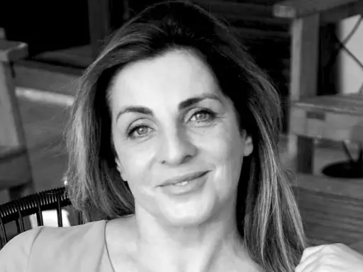 Ritratto in bianco e nero di una donna sorridente, con i capelli lunghi e mossi. "Ciao, come stai?" è una domanda inutile se il tuo sguardo è così sereno.