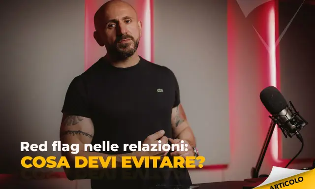 Uomo con tatuaggi parla di "red flag esempi" nelle relazioni. Microfono e luci rosse creano atmosfera da podcast.