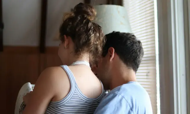 Un uomo sussurra all'orecchio di una donna, un momento intimo che rivela un'attrazione fortissima per una persona.