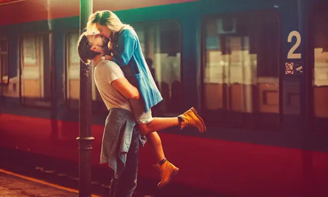 Un uomo solleva una donna in un bacio appassionato alla stazione. L'infatuazione significato è evidente nel loro abbraccio.