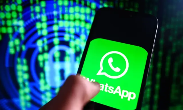 Un dito tocca lo schermo di uno smartphone con il logo WhatsApp, simbolo di cosa è una chat moderna. Sullo sfondo, un lucchetto digitale e codice binario suggeriscono sicurezza e comunicazione.