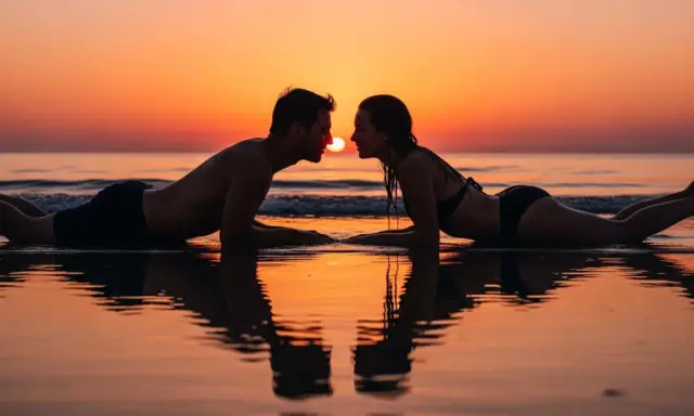 Coppia sdraiata sulla spiaggia al tramonto, sguardi intensi, si sente l'attrazione tra due persone.
