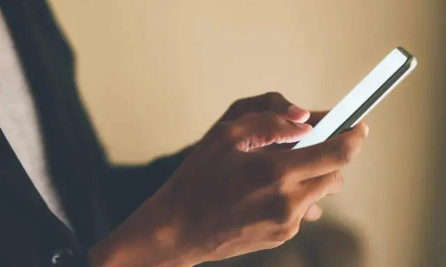 Mani che scorrono su uno smartphone, forse applicando la tattica di non rispondere ai messaggi per un po' di pace.