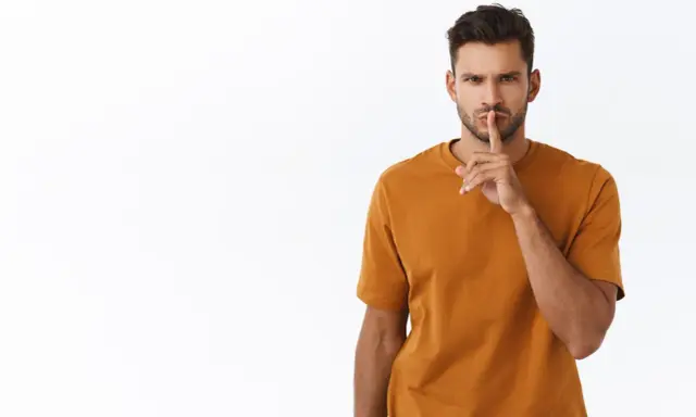Uomo con dito sulle labbra, sguardo intenso. Sembra dire "shhh", forse perché un uomo non risponde ai messaggi.
