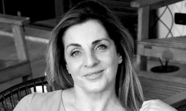 Ritratto in bianco e nero di una donna sorridente, con i capelli lunghi e mossi. "Ciao, come stai?" è una domanda inutile se il tuo sguardo è così sereno.