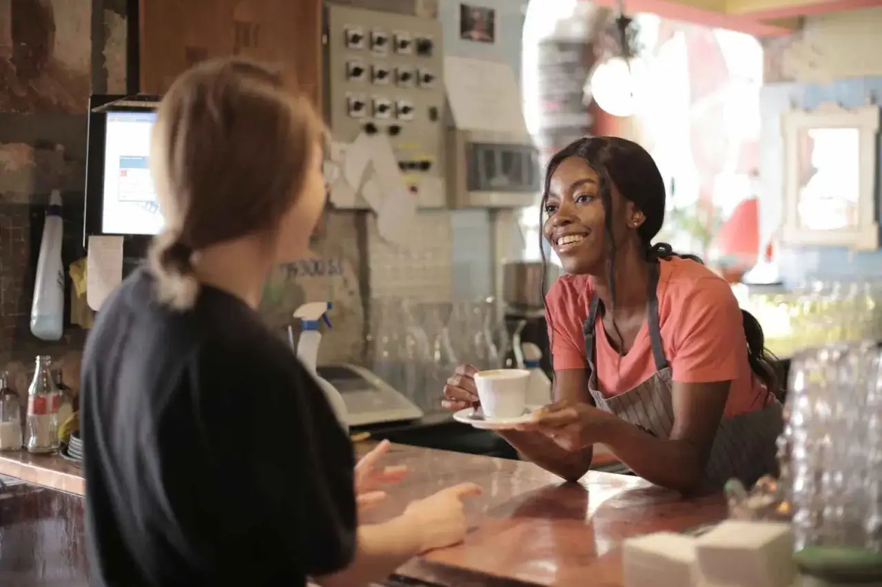 Cameriera sorridente porge un caffè. Se ti chiede di uscire, gli piaci.