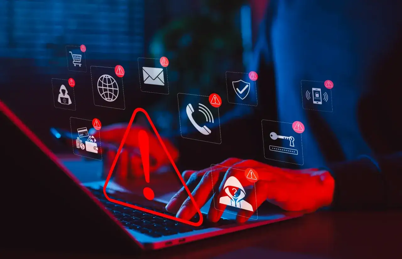 Mani su tastiera, icone di avviso e un punto esclamativo rosso indicano rischi di sicurezza online, come un digichat compromesso.