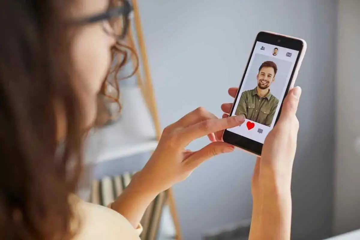 Donna usa il telefono per trovare un match su Tinder. Un profilo con un uomo sorridente appare sullo schermo, pronto per un icebreaker.