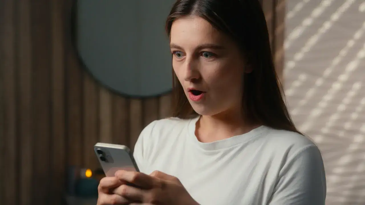 Sorpresa sul volto di una giovane donna che guarda il telefono. Sembra che chi fa orbiting ritorna, con una notizia inaspettata.