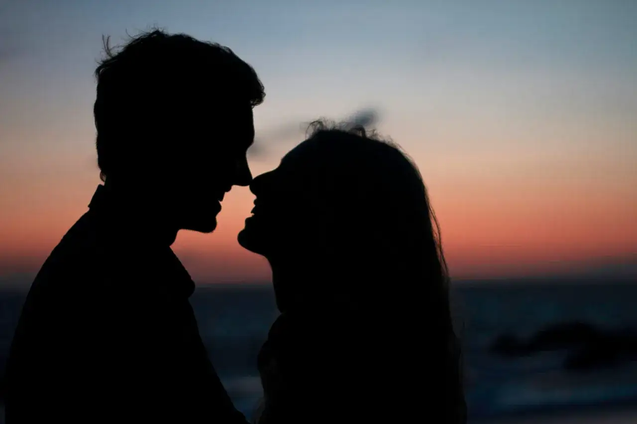 Silhouette di una coppia al tramonto, con un intenso sguardo innamorato che cattura l'essenza del loro amore.